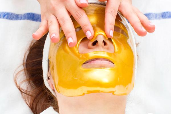 Woman getting gold facemask put on