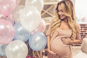 Pregnant woman standing next to balloons
